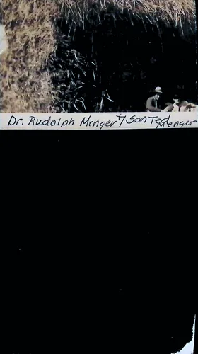 Dr. Rudolph Menger & son (identification) — Dark, partly overexposed photo (largely black) showing two men in hats at lower right amid brush or thatch. Handwritten caption along a strip reads: "Dr. Rudolph Menger & Son Te[?] Menger".