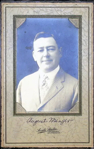 August Menger (portrait) — Studio portrait of a man in a pinstriped suit and patterned tie, mounted in a decorative card frame. Signed below in ink "August Menger". Studio imprint reads "Smith's Studio[?] San Antonio, Tex.".