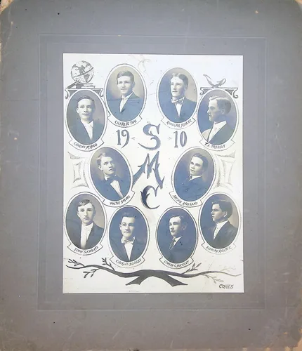 SMC class composite 1910 — 1910 — Oval-framed photo composite of eleven young men around a central "19 S M C 10" monogram, signed "Cones" at lower right. Name banners under each portrait include "Charlie Tips", "Adolph Mosel[?]", "E.A. Tressy[?]", "Walter Stupp[?]", "Arthur Ana[?]land", "Edward Schulz[?]", "David C. Botello[?]", and others; several are illegible.